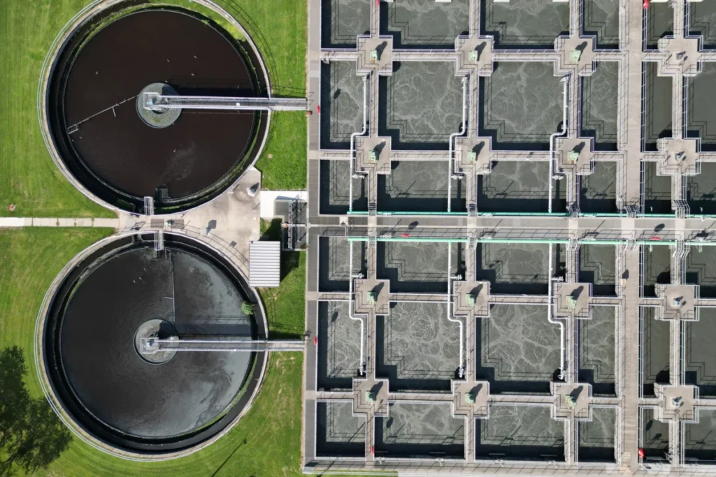 An aerial view of a modern wastewater treatment plant with circular clarifier tanks and filtration basins