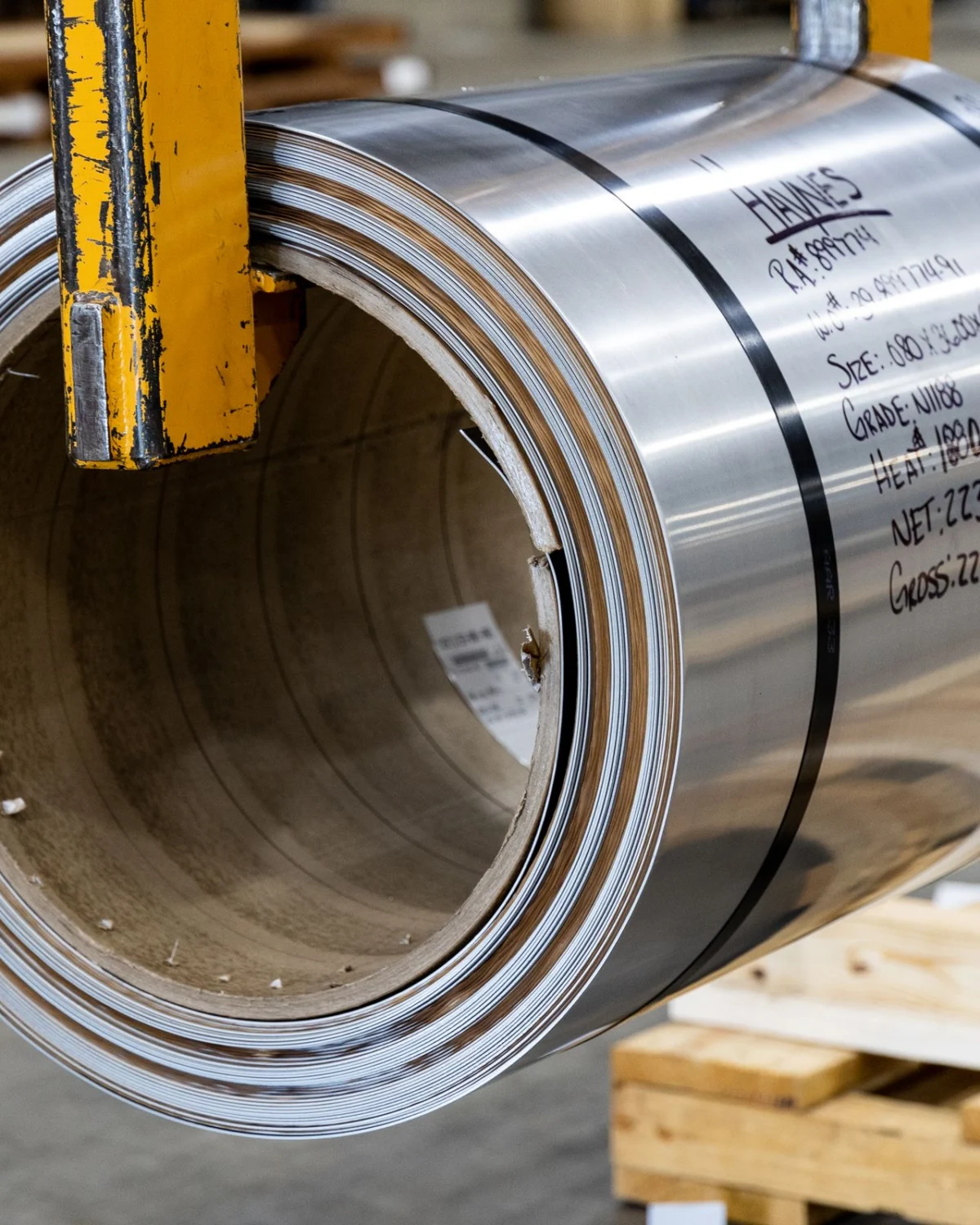 A bright coil of steel sheet on a wooden pallet, the kind of finished metal rust preventatives protect in storage and shipping