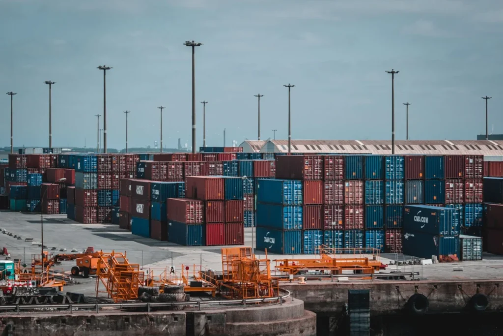 Stacked shipping containers at a cargo port, where parts protected by rust preventatives face long overseas transit