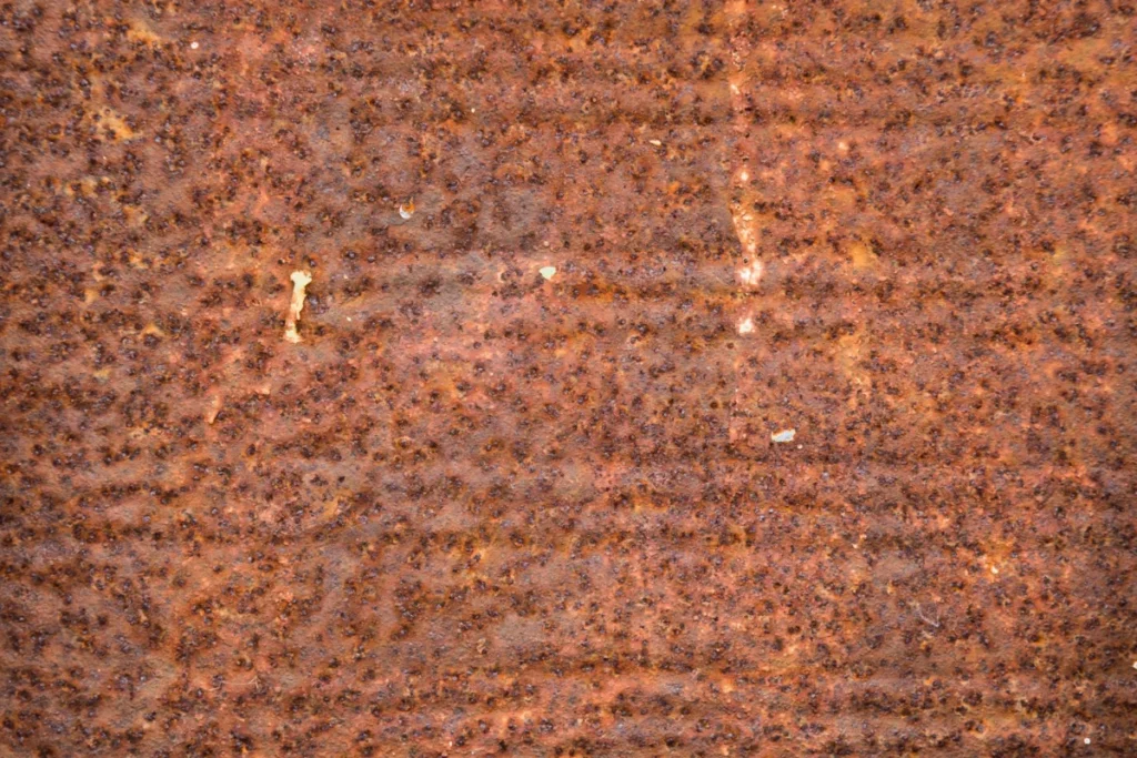 Close-up of a steel surface covered in orange-brown rust, the corrosion rust preventatives are chosen to stop