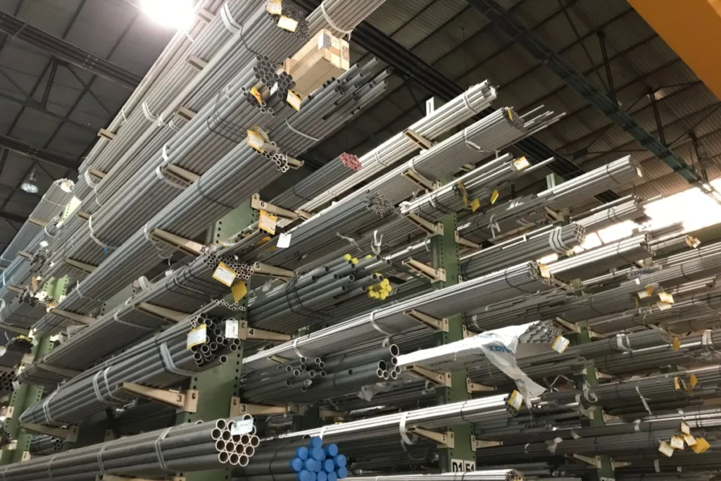 Metal tubes and bar stock stored on tall cantilever racks inside a warehouse